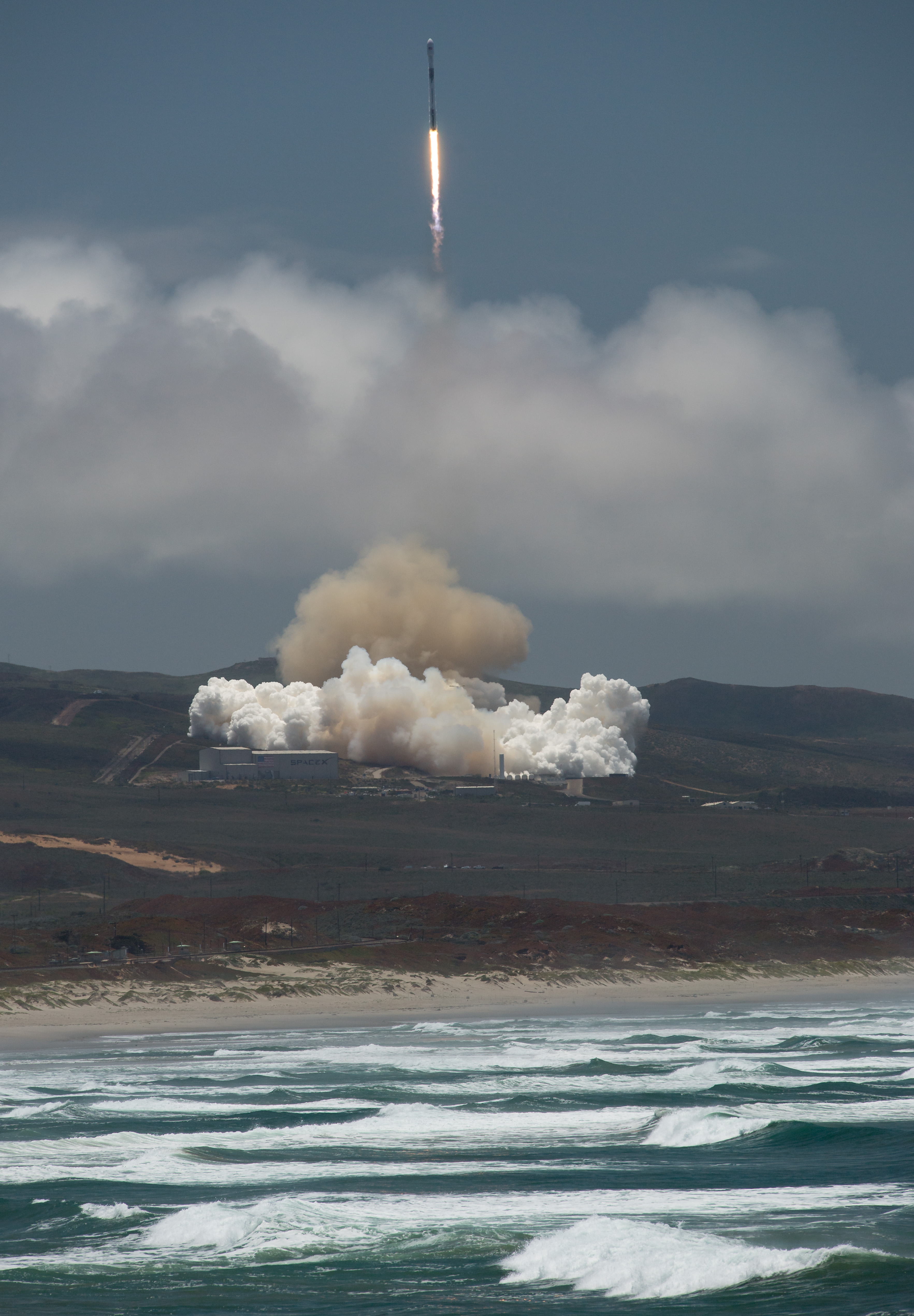 The rocket carrying GRACE-FO blasts off from the launch pad, with the ocean in the foreground.