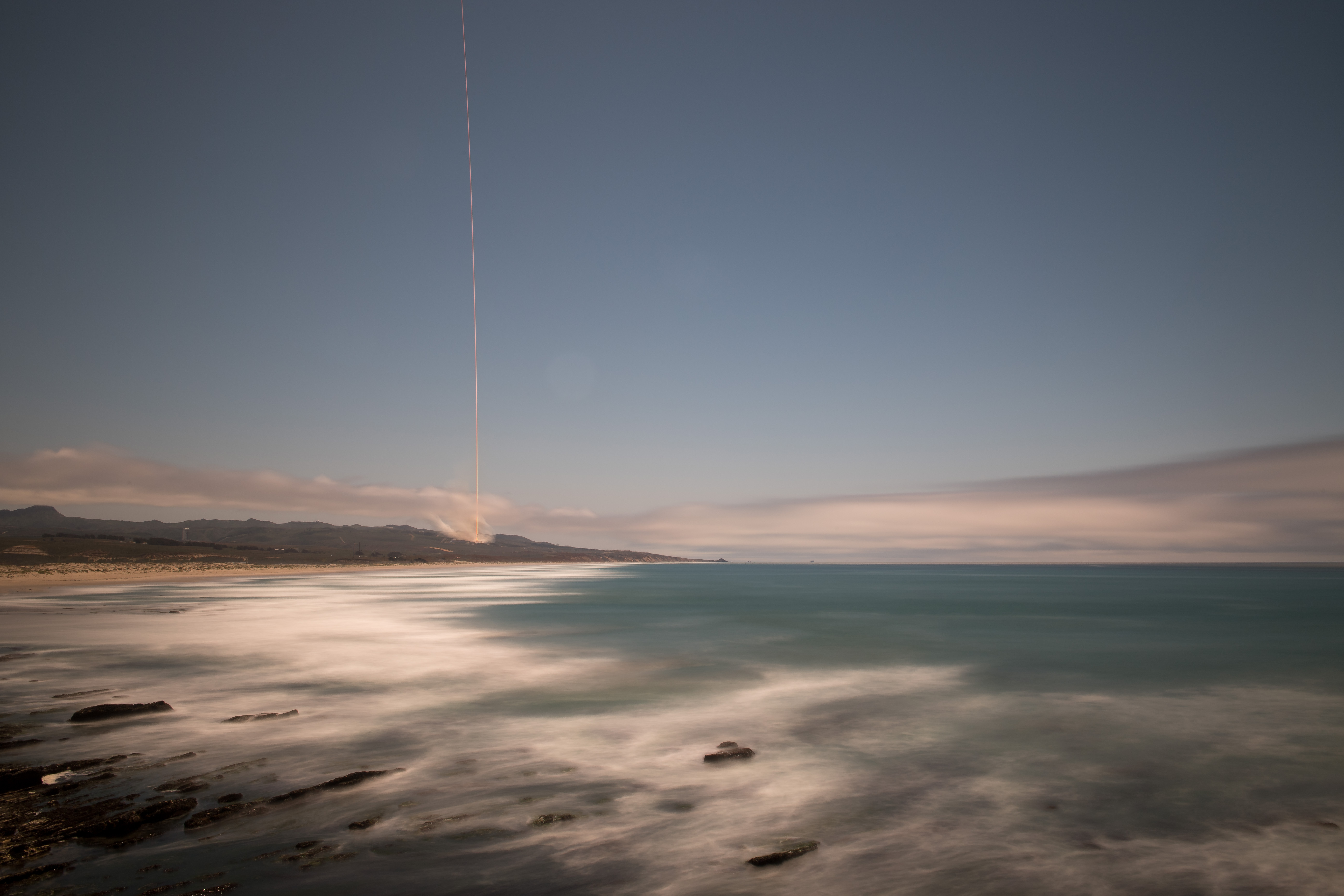The rocket's blaze is seen across the sky in this long exposure view with the ocean in the foreground.