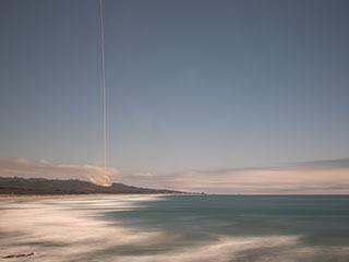 The rocket's blaze is seen across the sky in this long exposure view with the ocean in the foreground.